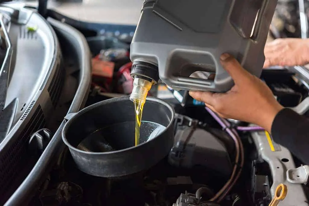 Our Mechanic Pouring New Oil as a Part of an Oil Change During a Periodic Vehicle Maintenance Service